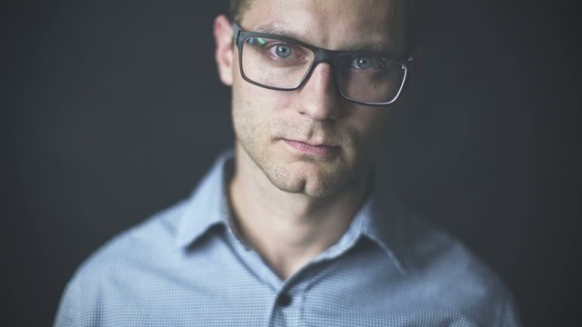 Young man in glasses having a serious look on black background