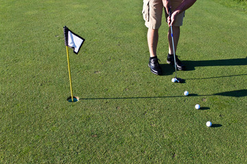 Golfer practicing putting with several golf balls