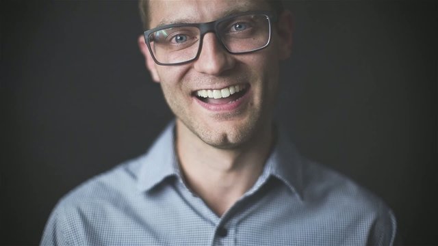 Young handsome man in glasses laughing in front of camera