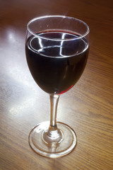 A glass of Red Wine on a wooden table.