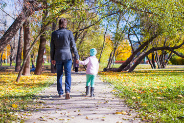 Young father and little girl walking in autumn park