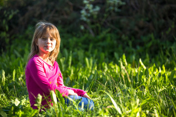 Fototapeta premium Portrait of little girl in the grass outdoors.