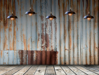 Empty room interior. Lamp hangs in rusted galvanized iron plate on background with wooded floor. ...