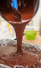 pouring mixture of chocolate eggs and flour preparing for bake b
