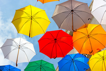 Colorful floating umbrellas against a blue sky