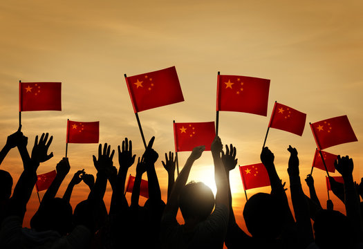 Group of People Waving Chinese Flags in Back Lit