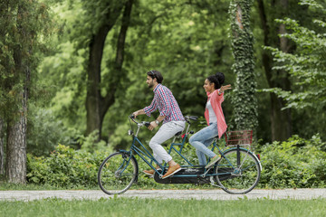 Young couple riding on the tandem bicycle