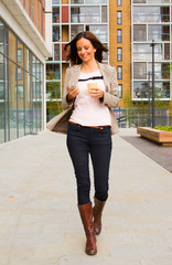 Obraz premium young woman walking sending a message and drinking coffee