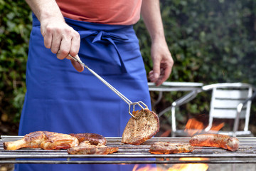 Mann grillt Fleisch im Garten