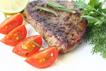 serving of meat with vegetables on a plate of white background