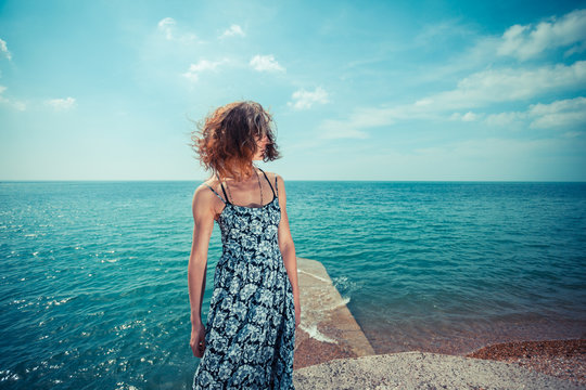 Young woman wearing a dress standing by the ocean