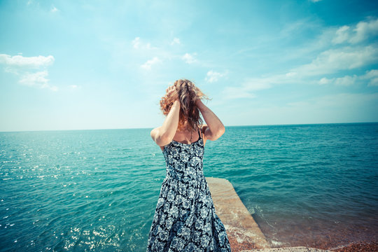 Young woman in dress standing by the ocean