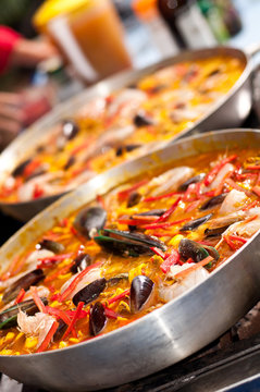 Two spanish paellas being cooked in the kitchen