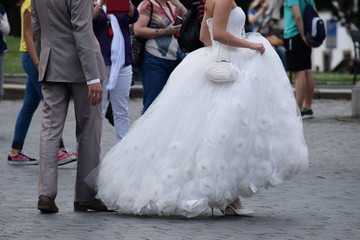 Naklejka na ściany i meble Beautiful bride in a luxurious white dress. The first walk of the newlyweds surrounded by admiring people. Wedding. Stock photo.