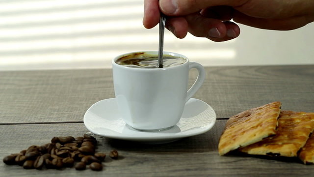 stirring coffee, a cup of coffee costs on a wooden table