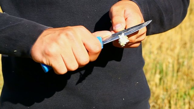 The teenager hands with the knife on a field