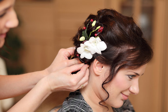 Fototapeta Fryzjerka wpina kwiat we włosy dziewczyny.