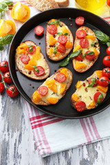 Tasty bruschetta with tomatoes on pan, on old wooden table