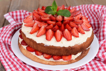 Delicious biscuit cake with strawberries on table close-up
