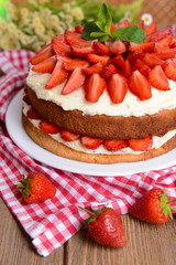 Delicious biscuit cake with strawberries on table close-up