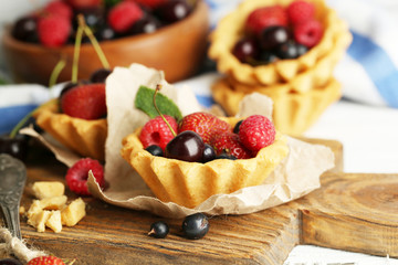 Tasty tartlets with berries on wooden table