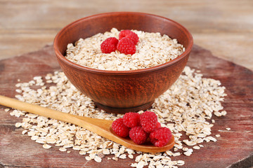 Big brown bowl with oatmeal and berries on a wooden table