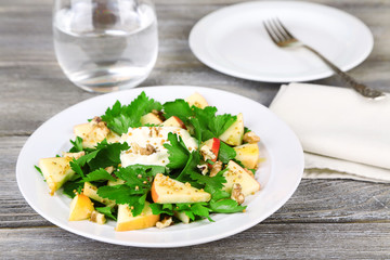 Green salad with apples, walnuts and cheese on wooden