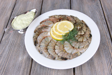 Round white plate of prawns with dill, lemon and sauce
