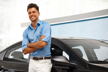 Car Showroom. Happy Man near Car of His Dream.