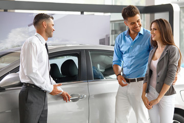 Car Showroom. Young Couple Buying a New Car at Dealership.