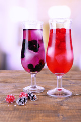 Glasses of cold berry cocktail on wooden table