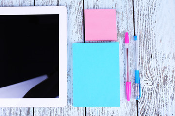 Tablet, notebook and pens on wooden background