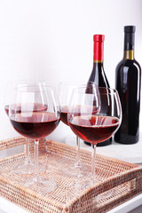 Glasses and wine bottle on tray in room