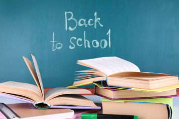 School supplies on table on blackboard background