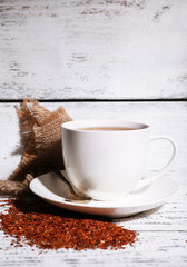 Cup of tasty rooibos tea, on old white wooden table