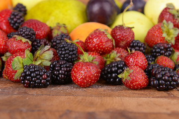 Ripe fruits and berries on wooden background