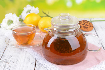 Teapot and cup of tea on table on bright background