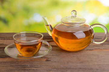 Teapot and cup of tea on table on bright background