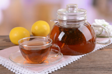 Teapot and cup of tea on table on light background