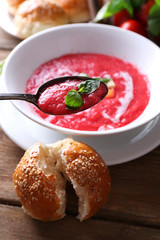Gazpacho soup in spoon and bowl on  wooden background