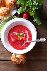 Gazpacho soup in spoon and bowl on  wooden background