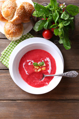 Gazpacho soup in spoon and bowl on  wooden background