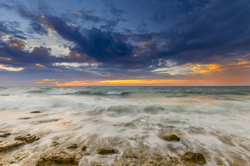 a fiery sunset and the waves lapping on the rocky shore