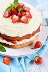 Delicious biscuit cake with strawberries on table close-up