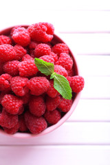 Ripe sweet raspberries in bowl on table close-up