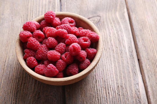 Ripe sweet raspberries in bowl on table close-up