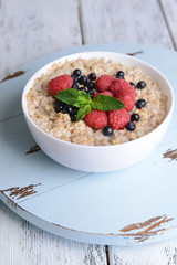 Tasty oatmeal with berries on table close-up