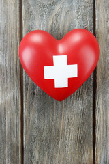 Red heart with cross sign on wooden background