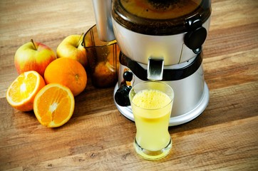 Juicer and orange juice on wooden background