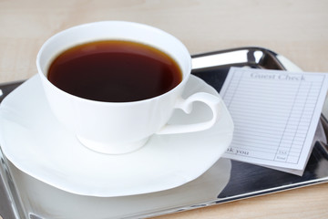 Check and cup of coffee on tray close-up